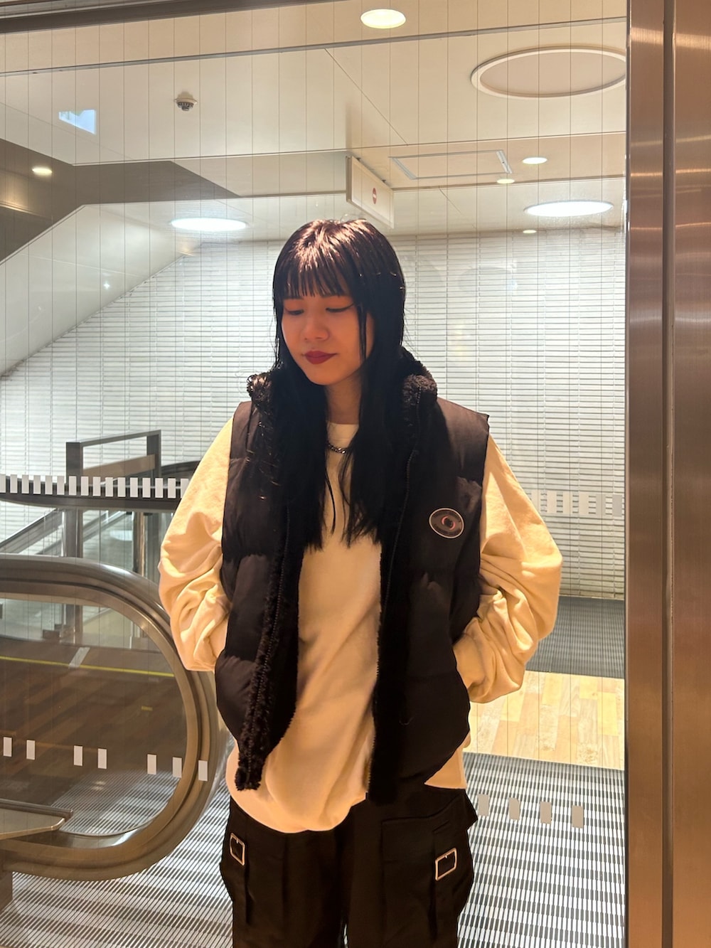 ブラック系のブーツ、ブラック系のダウンベスト、ホワイト系のTシャツ/カットソーを着用したレディースの秋コーディネートの5枚目の写真