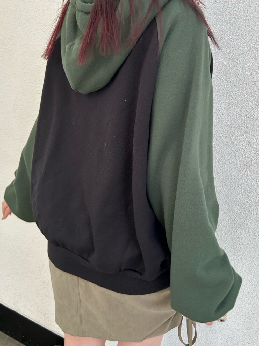 ブラック系のブーツ、グリーン系のスカート、ブラック系のパーカーを着用したレディースの冬コーディネートの6枚目の写真