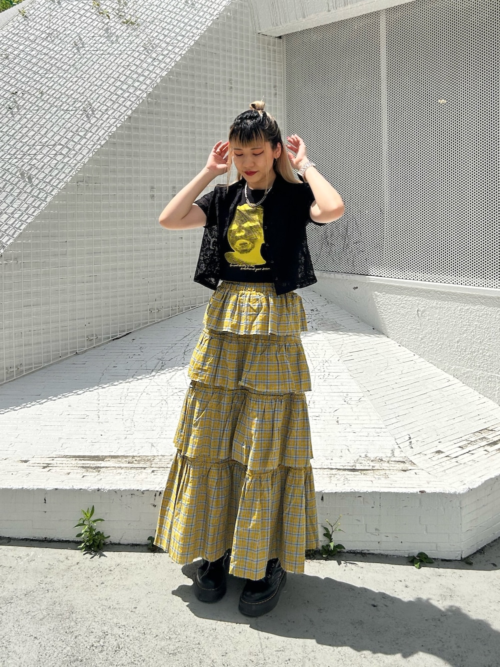 ブラック系のブーツ、イエロー系のスカート、ブラック系のTシャツ/カットソーを着用したレディースの春コーディネートの2枚目の写真