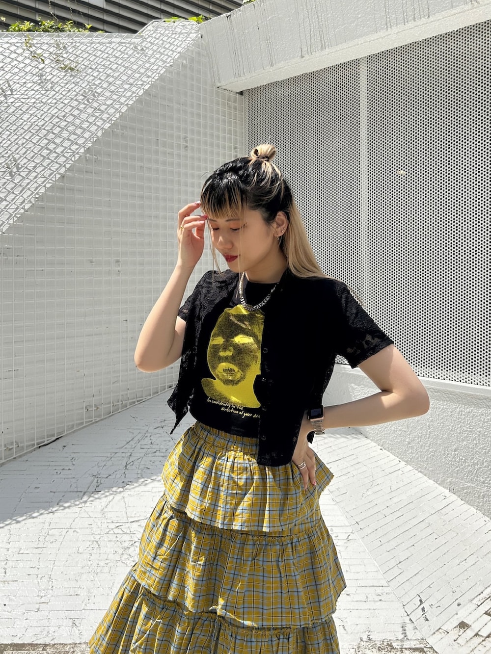 ブラック系のブーツ、イエロー系のスカート、ブラック系のTシャツ/カットソーを着用したレディースの春コーディネートの4枚目の写真