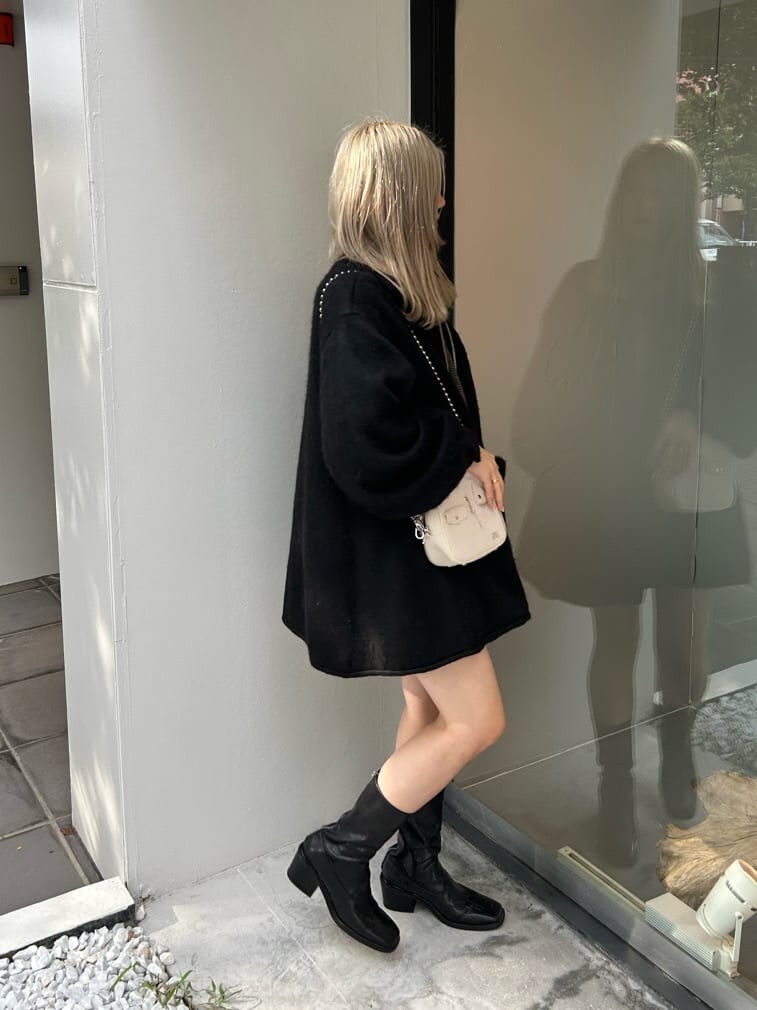 ブラック系のブーツ、ホワイト系のハンドバッグ、ブラック系のデニムパンツを着用したレディースの秋コーディネートの3枚目の写真