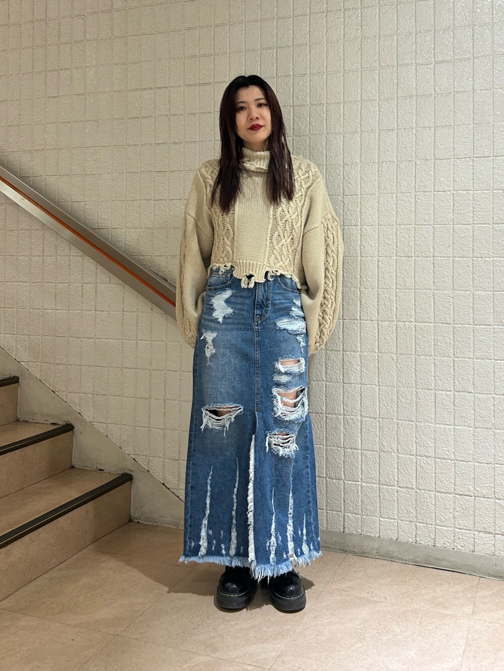 ブラック系のブーツ、ブルー系のデニムスカート、ホワイト系のニット/セーターを着用したレディースの冬コーディネートの2枚目の写真