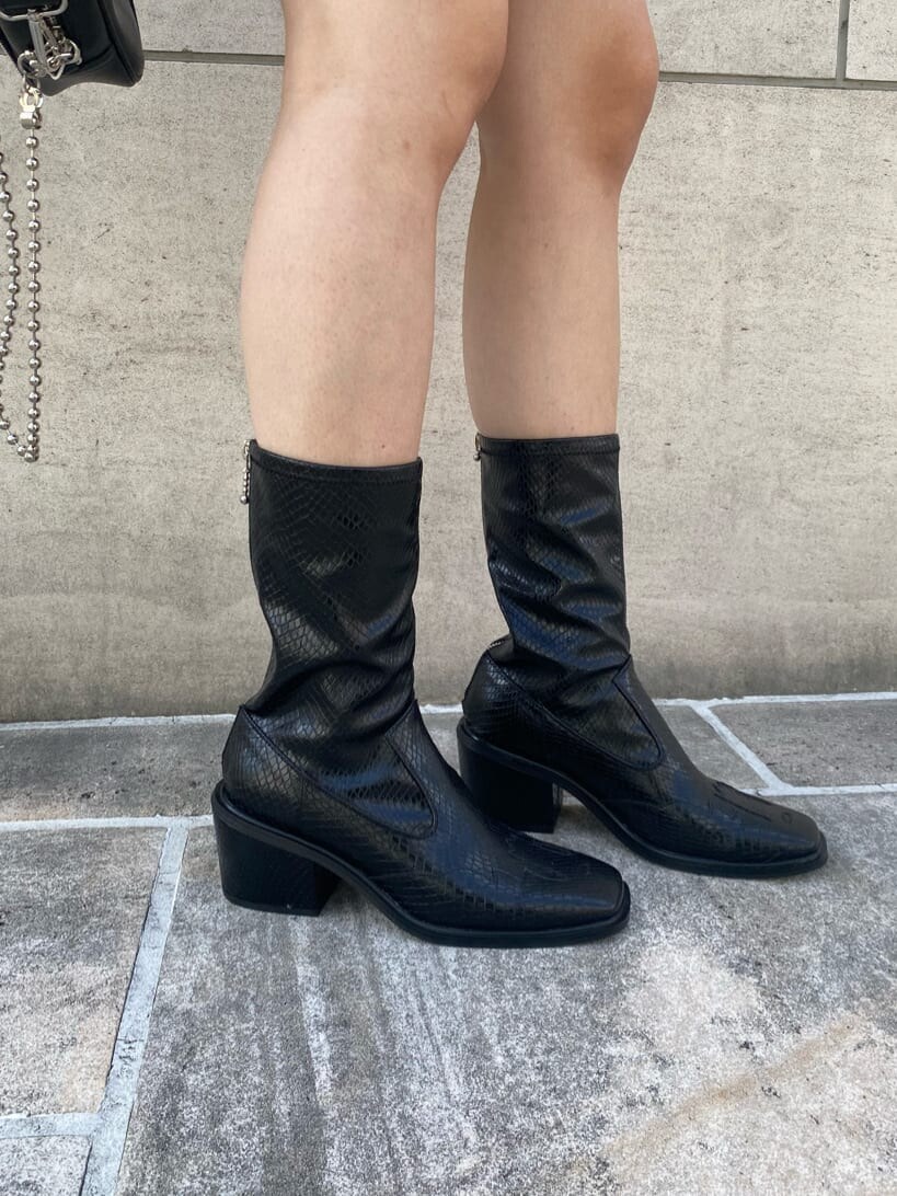 ブラック系のハンドバッグ、ブラック系のブーツ、ホワイト系のベストを着用したレディースの秋コーディネートの8枚目の写真