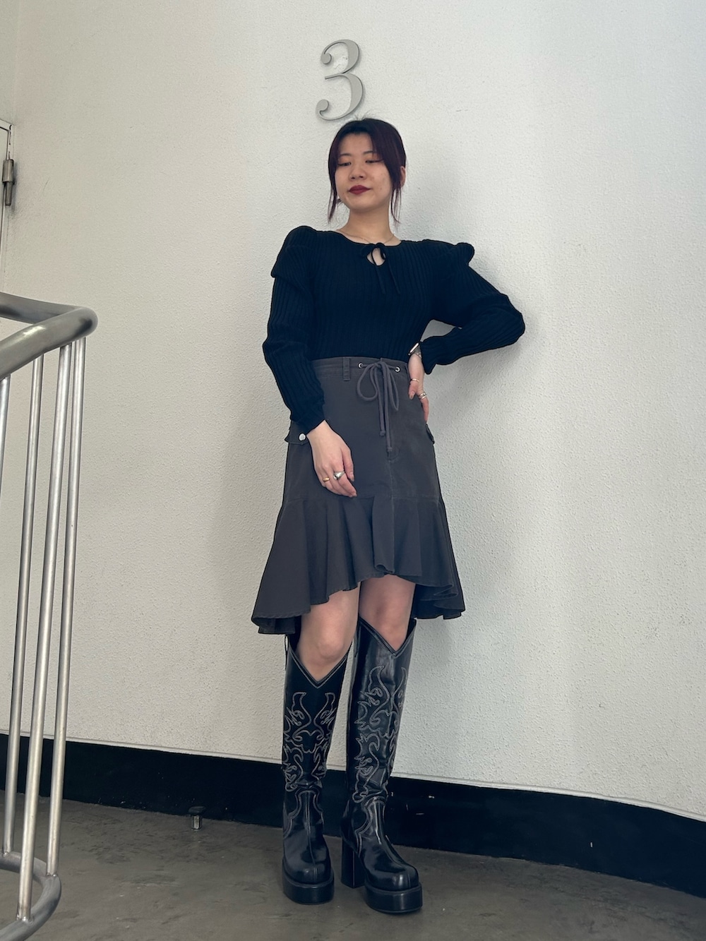 ブラック系のブーツ、ブラック系のスカート、ブラック系のニット/セーターを着用したレディースの冬コーディネートの2枚目の写真