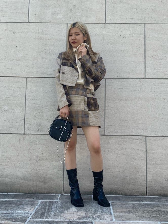 ブラック系のハンドバッグ、ブラック系のブーツ、ホワイト系のベストを着用したレディースの秋コーディネートの2枚目の写真