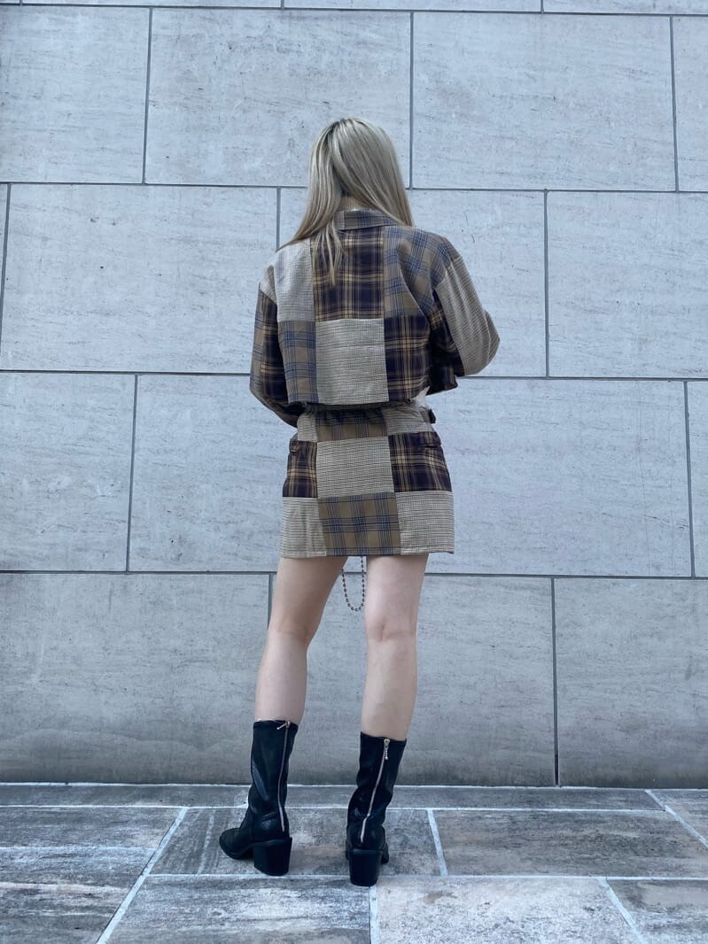 ブラック系のハンドバッグ、ブラック系のブーツ、ホワイト系のベストを着用したレディースの秋コーディネートの3枚目の写真