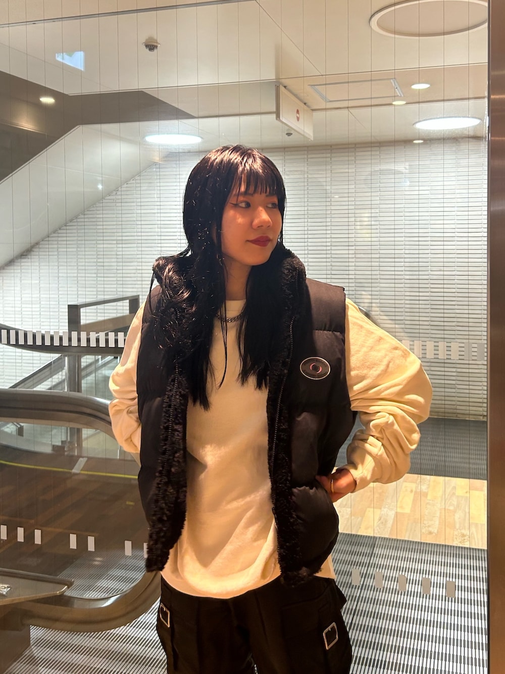 ブラック系のブーツ、ブラック系のダウンベスト、ホワイト系のTシャツ/カットソーを着用したレディースの秋コーディネートの4枚目の写真