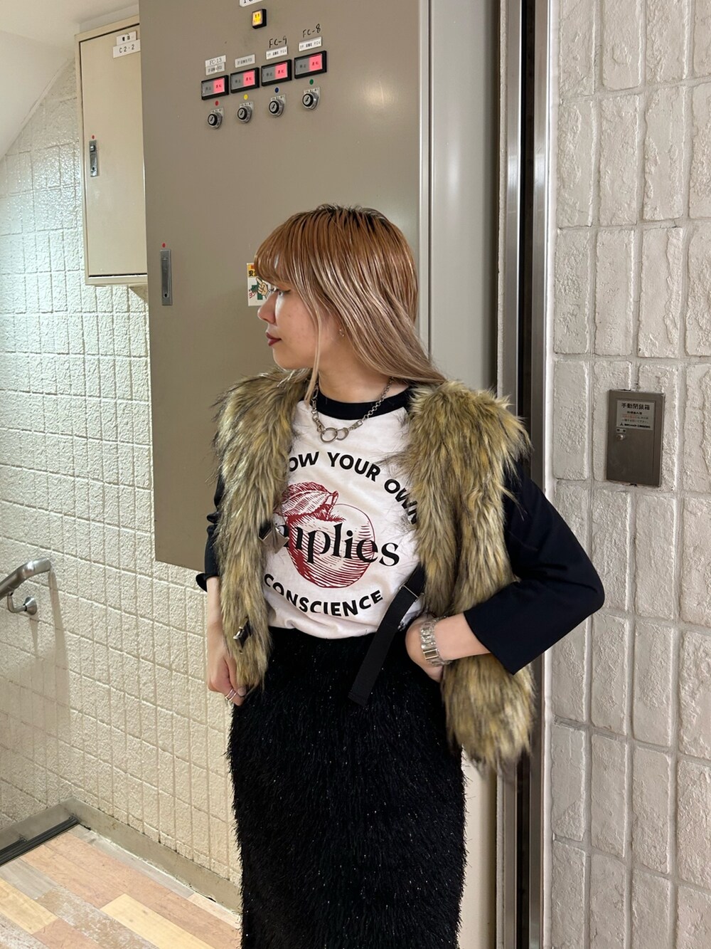 ブラック系のスカート、ブラック系のブーツ、ベージュ系のベストを着用したレディースの秋コーディネートの5枚目の写真