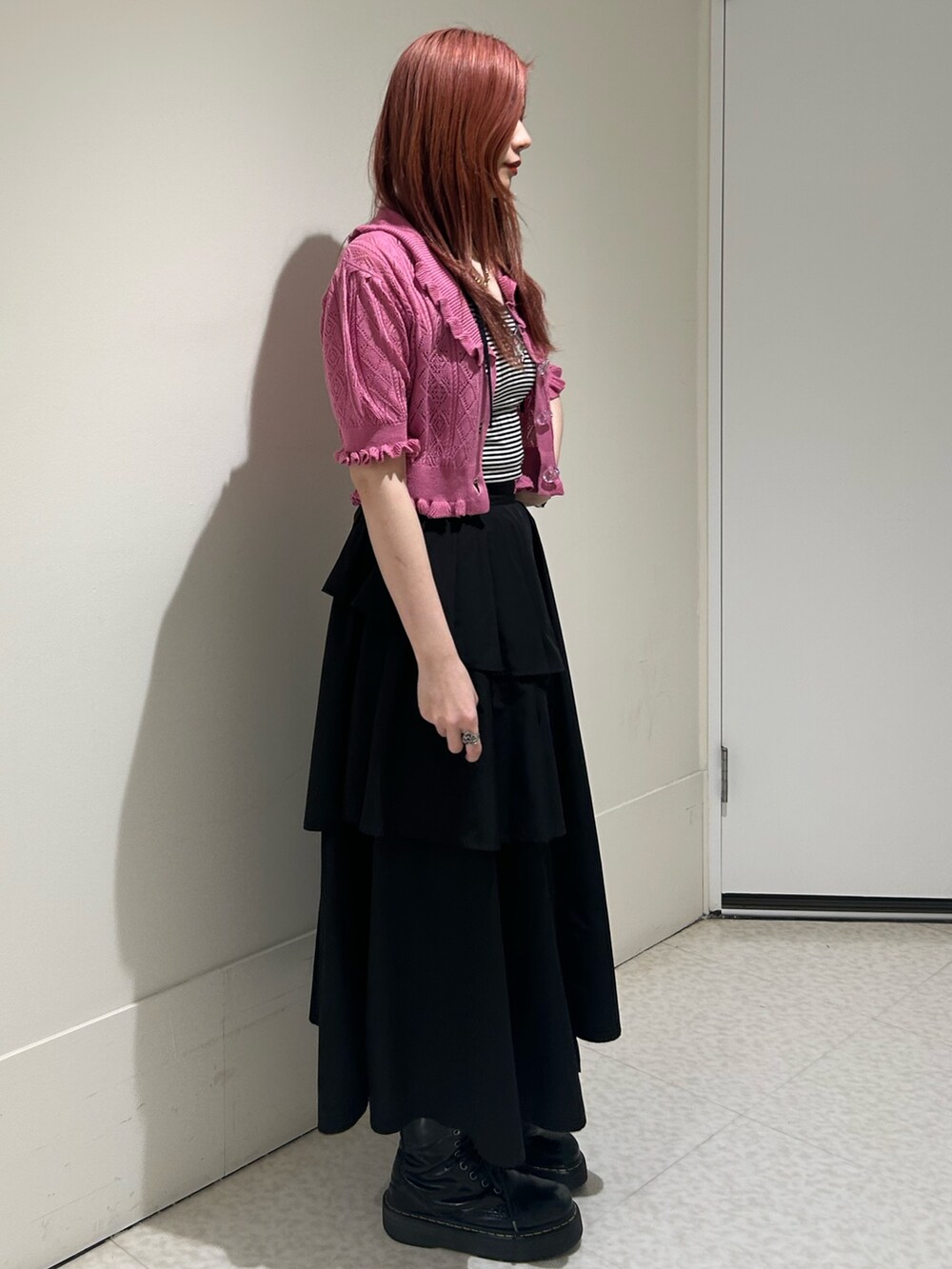 ブラック系のスカート、ブラック系のブーツ、ピンク系のカーディガン/ボレロを着用したレディースの春コーディネートの2枚目の写真