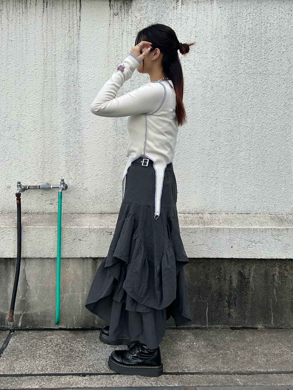 ブラック系のブーツ、ホワイト系のTシャツ/カットソー、グレー系のスカートを着用したレディースの秋コーディネートの2枚目の写真