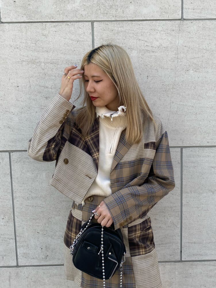 ブラック系のハンドバッグ、ブラック系のブーツ、ホワイト系のベストを着用したレディースの秋コーディネートの4枚目の写真