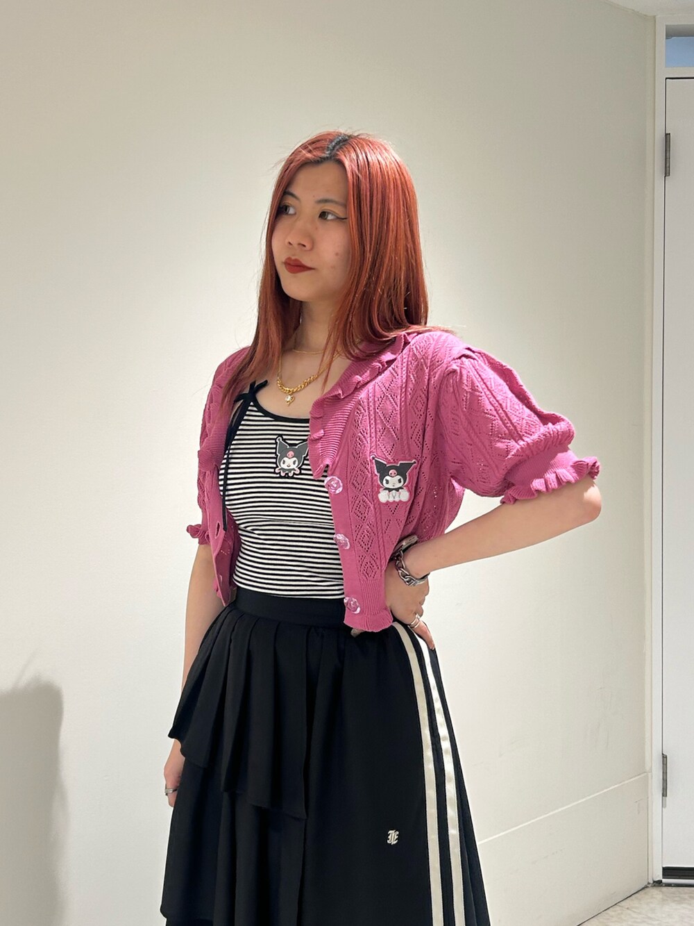 ブラック系のスカート、ブラック系のブーツ、ピンク系のカーディガン/ボレロを着用したレディースの春コーディネートの4枚目の写真