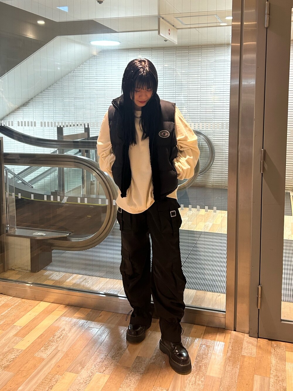 ブラック系のブーツ、ブラック系のダウンベスト、ホワイト系のTシャツ/カットソーを着用したレディースの秋コーディネートの2枚目の写真