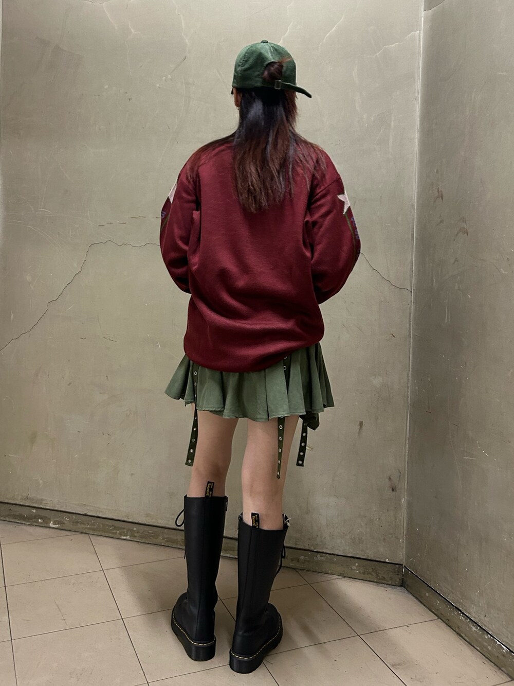ブラック系のブーツ、レッド系のニット/セーター、グリーン系のスカートを着用したレディースの秋コーディネートの4枚目の写真