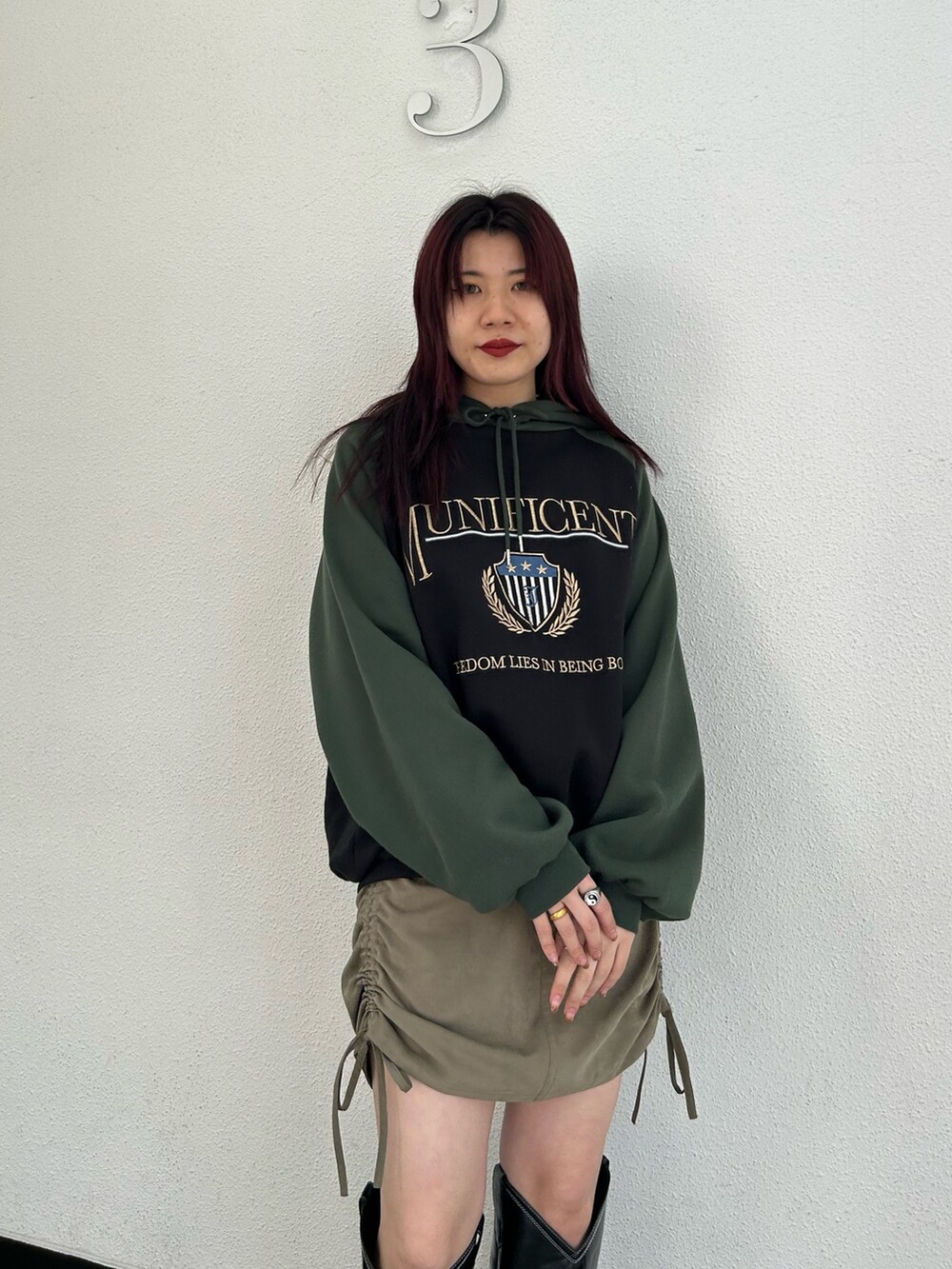 ブラック系のブーツ、グリーン系のスカート、ブラック系のパーカーを着用したレディースの冬コーディネートの4枚目の写真