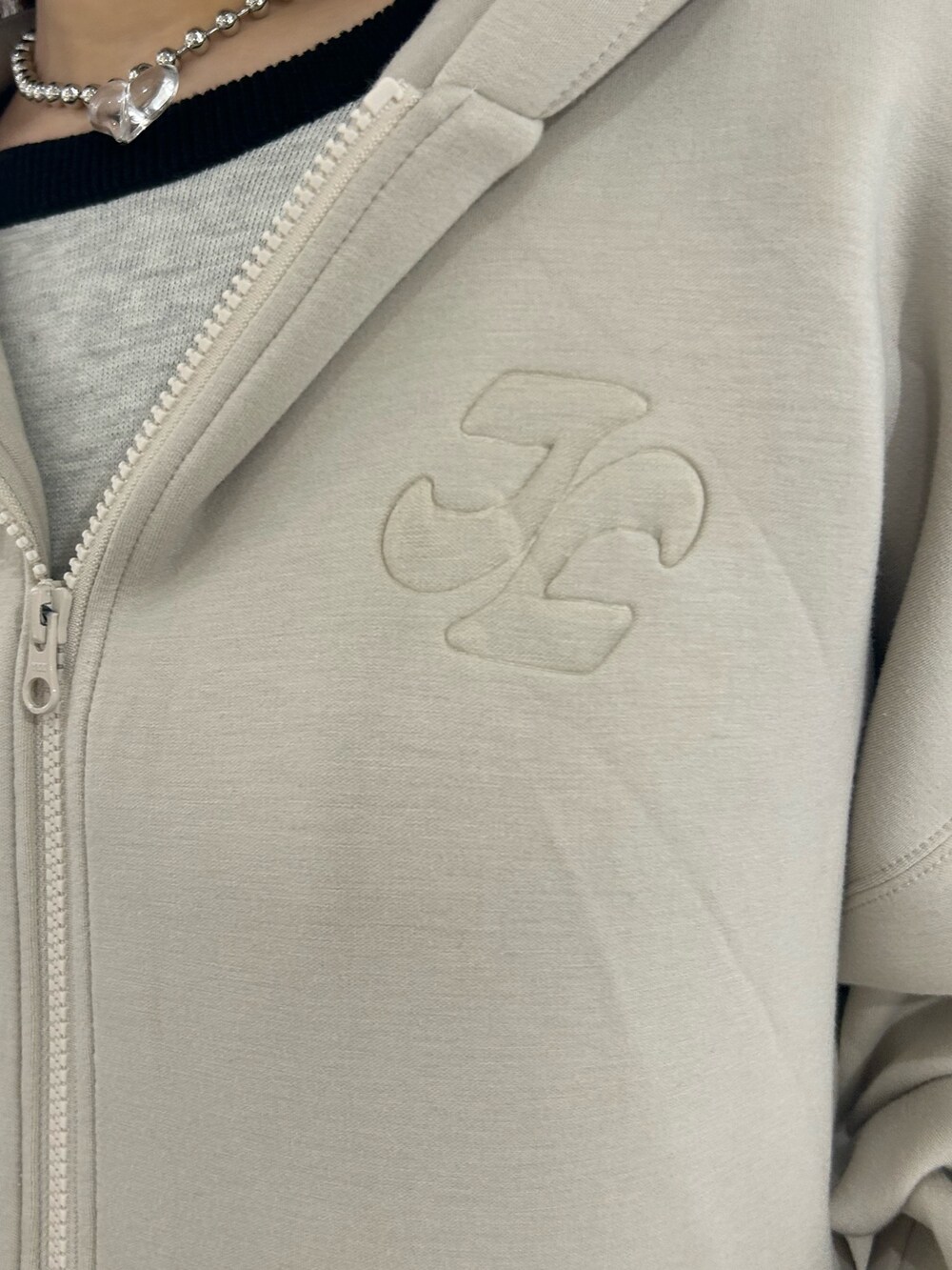 ブラック系のデニムパンツ、ホワイト系のパーカー、ホワイト系のニット/セーターを着用したレディースの春コーディネートの4枚目の写真