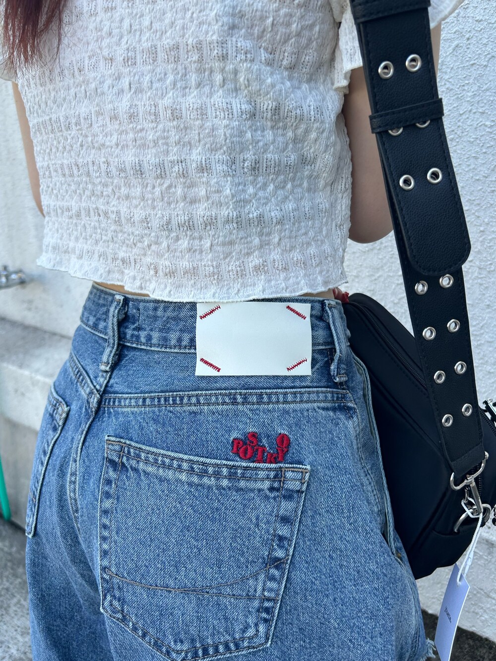 ブルー系のデニムパンツ、ブラック系のブーツ、ブラック系のショルダーバッグを着用したレディースの秋コーディネートの8枚目の写真