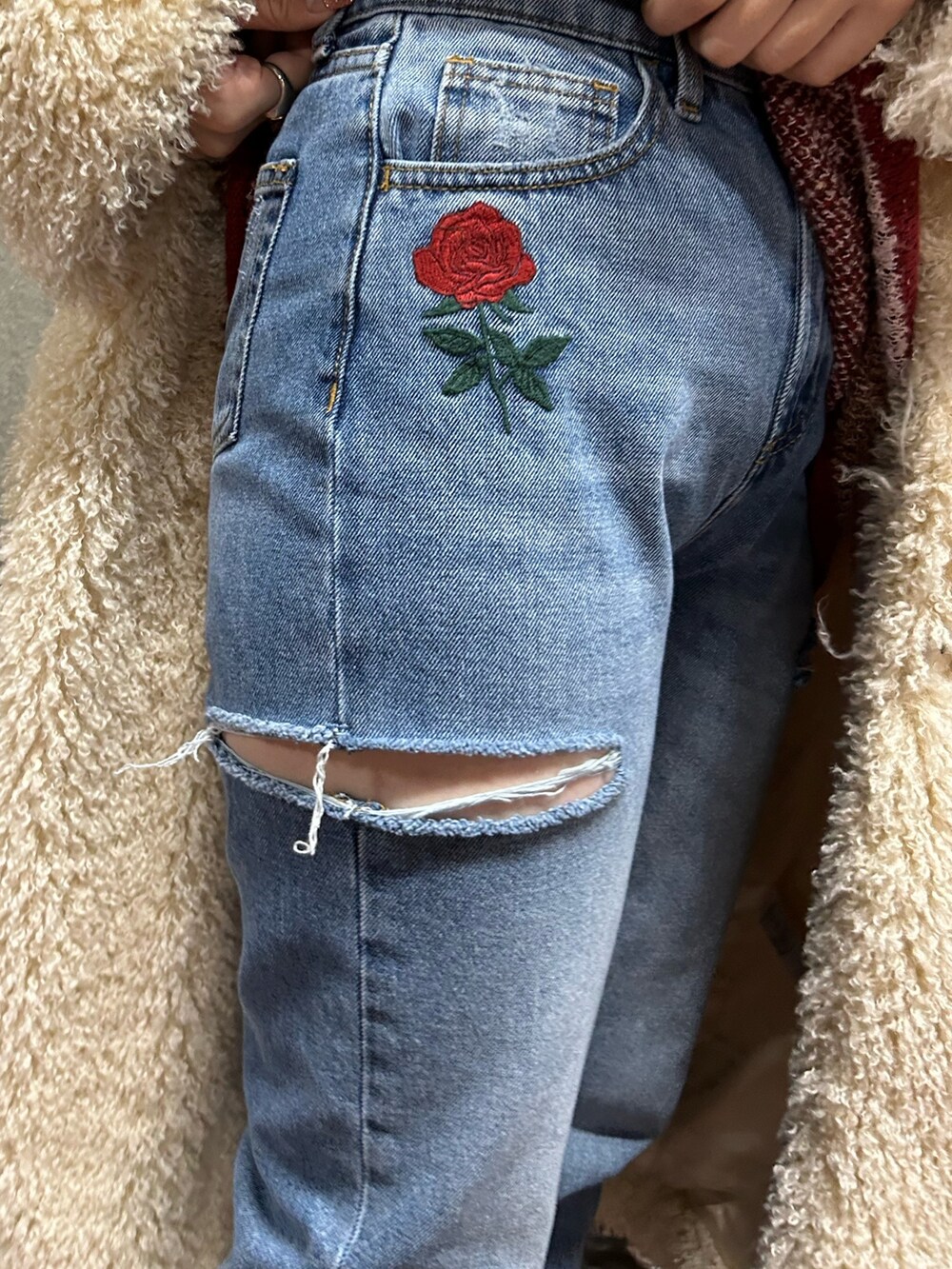 レッド系のニット/セーター、ブルー系のデニムパンツ、ホワイト系のその他アウターを着用したレディースの冬コーディネートの6枚目の写真