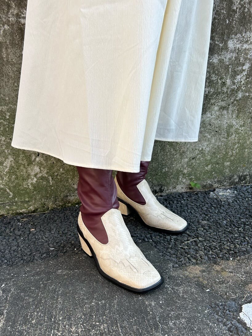 ホワイト系のその他アウター、ホワイト系のブーツ、ホワイト系のワンピースを着用したレディースの秋コーディネートの10枚目の写真