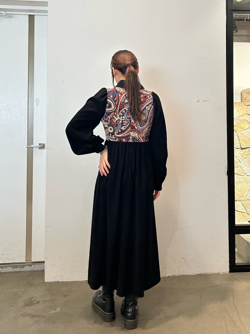 ブラック系のワンピース、ブラック系のブーツを着用したレディースの秋コーディネートの3枚目の写真