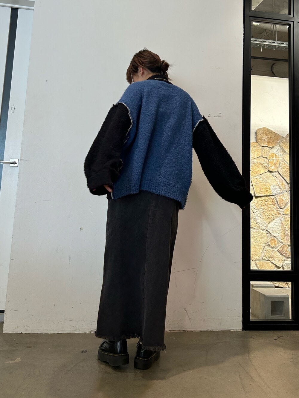 ブラック系のデニムパンツ、ブラック系のブーツ、ブラック系のニット/セーターを着用したレディースの秋コーディネートの2枚目の写真