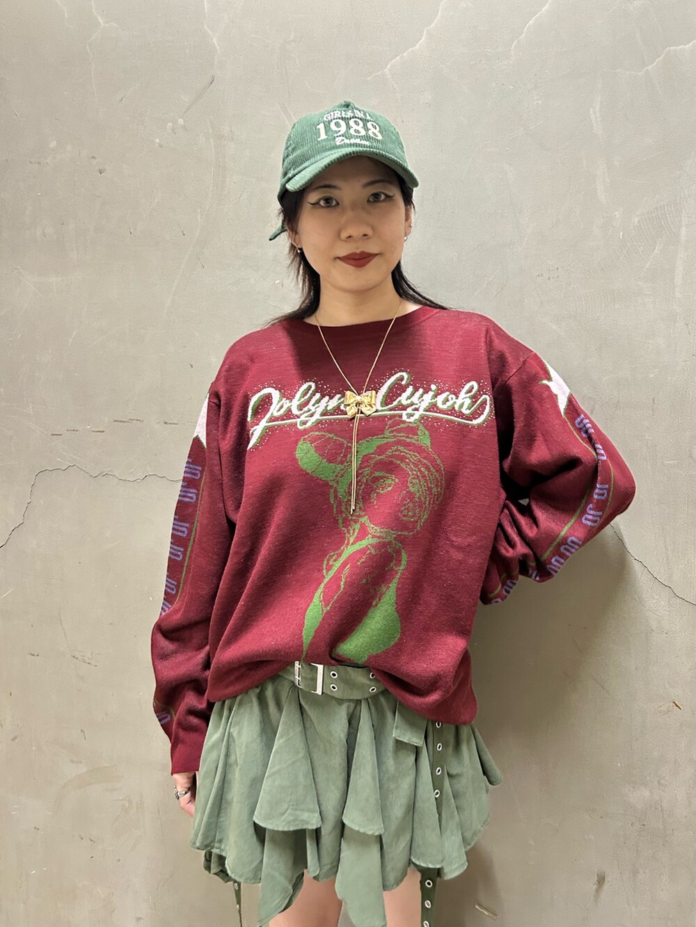 ブラック系のブーツ、レッド系のニット/セーター、グリーン系のスカートを着用したレディースの秋コーディネートの5枚目の写真