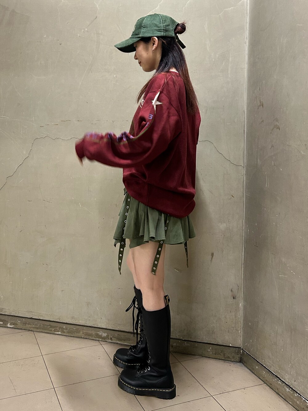 ブラック系のブーツ、レッド系のニット/セーター、グリーン系のスカートを着用したレディースの秋コーディネートの3枚目の写真