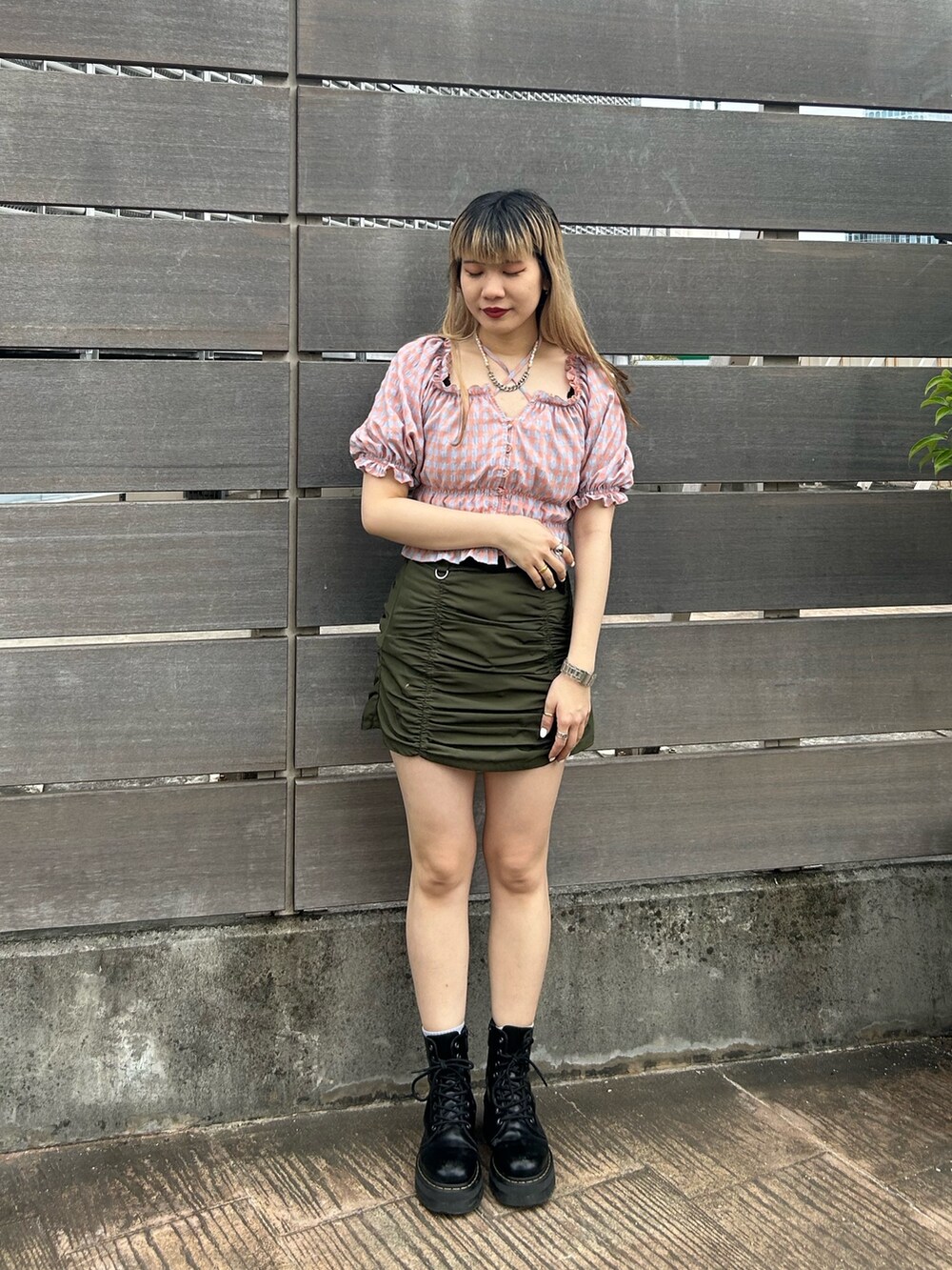 ブラック系のブーツ、オレンジ系のシャツ/ブラウス、グリーン系のスカートを着用したレディースの夏コーディネートの2枚目の写真