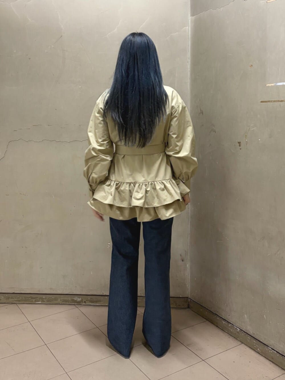 ベージュ系のワンピース、ホワイト系のTシャツ/カットソー、ブルー系のデニムパンツを着用したレディースの春コーディネートの3枚目の写真