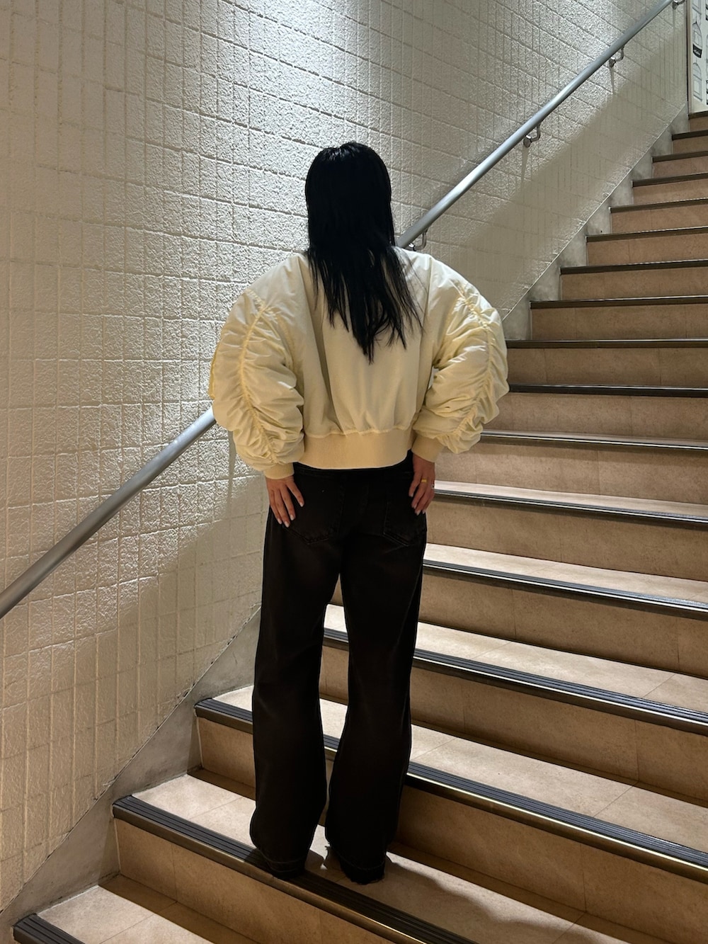 ベージュ系のブーツ、ブラック系のデニムパンツ、ホワイト系のMA-1を着用したレディースの秋コーディネートの3枚目の写真