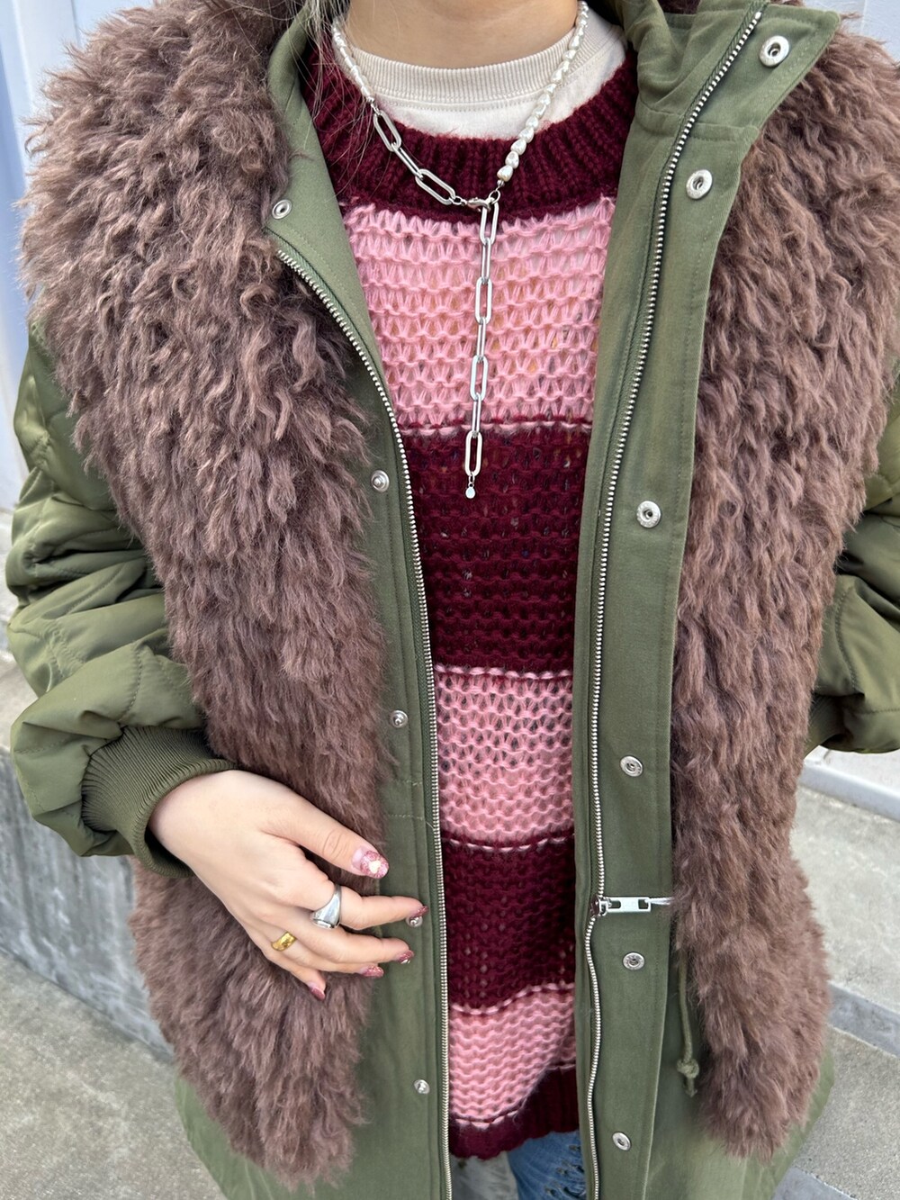 グリーン系のモッズコート、レッド系のニット/セーター、ホワイト系のTシャツ/カットソーを着用したレディースの秋コーディネートの6枚目の写真