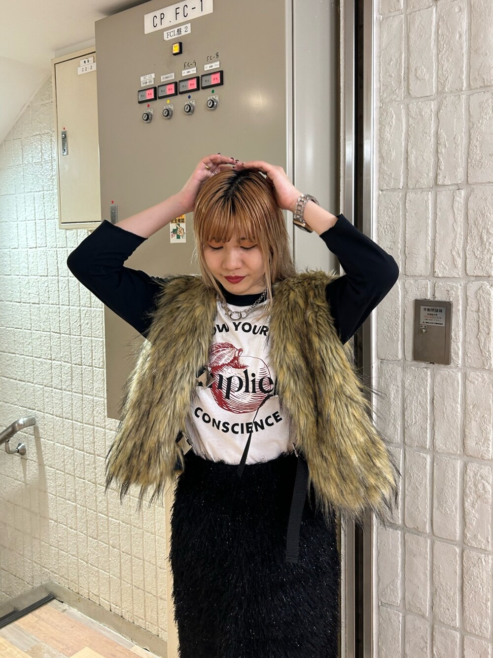 ブラック系のスカート、ブラック系のブーツ、ベージュ系のベストを着用したレディースの秋コーディネートの4枚目の写真