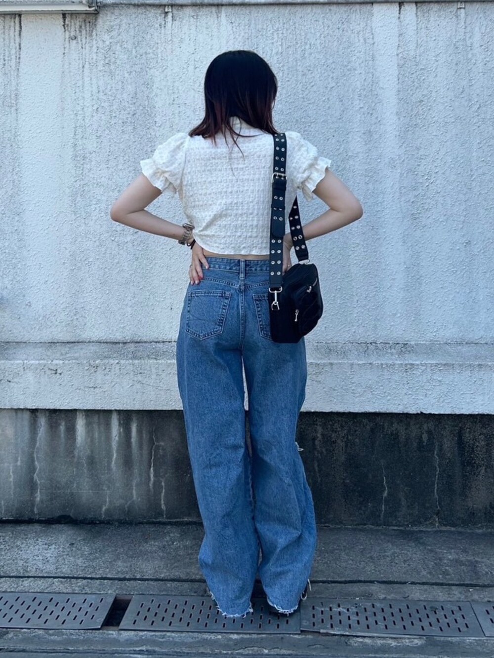 ブルー系のデニムパンツ、ブラック系のブーツ、ブラック系のショルダーバッグを着用したレディースの秋コーディネートの5枚目の写真