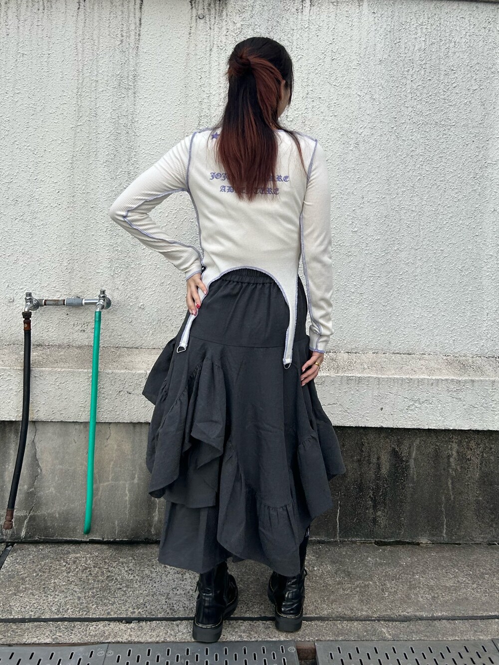 ブラック系のブーツ、ホワイト系のTシャツ/カットソー、グレー系のスカートを着用したレディースの秋コーディネートの3枚目の写真