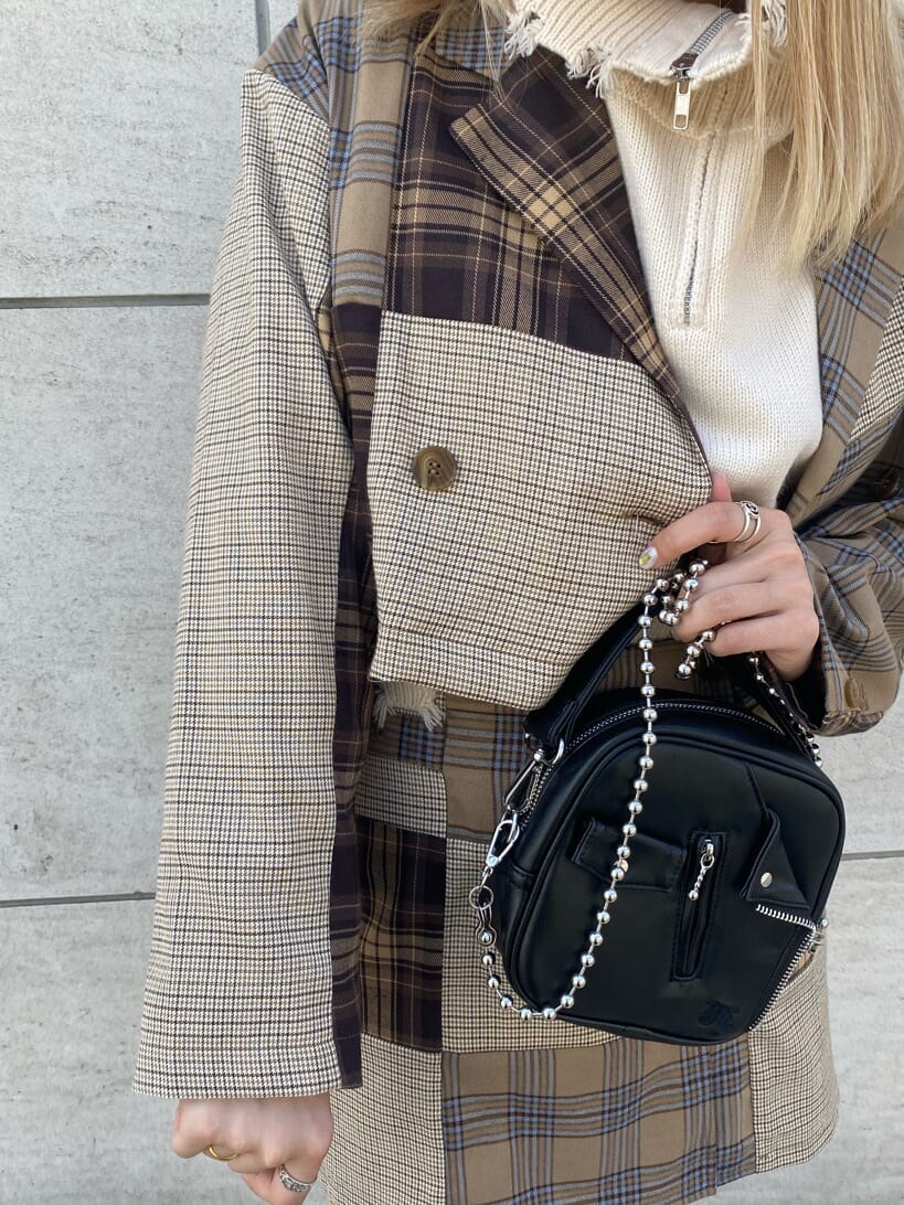 ブラック系のハンドバッグ、ブラック系のブーツ、ホワイト系のベストを着用したレディースの秋コーディネートの7枚目の写真