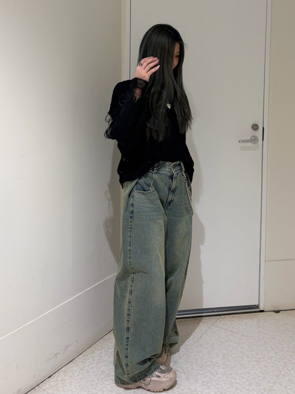 ブルー系のデニムパンツ、ブラック系のニット/セーター、シルバー系のネックレスを着用したレディースの春コーディネートの2枚目の写真
