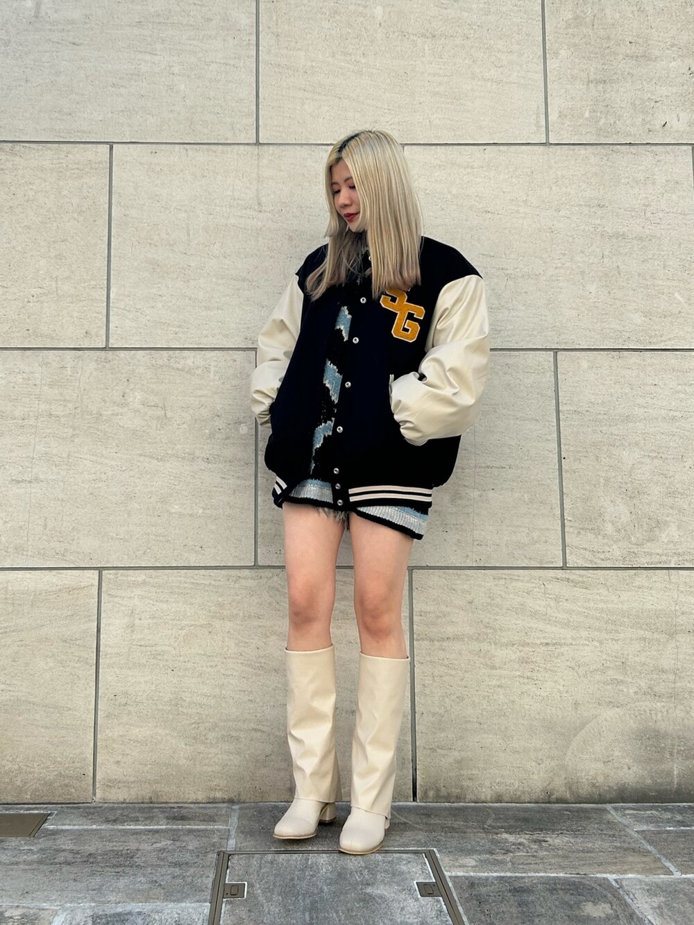 ブラック系のデニムパンツ、ホワイト系のブーツ、ブラック系のニット/セーターを着用したレディースの冬コーディネートの2枚目の写真