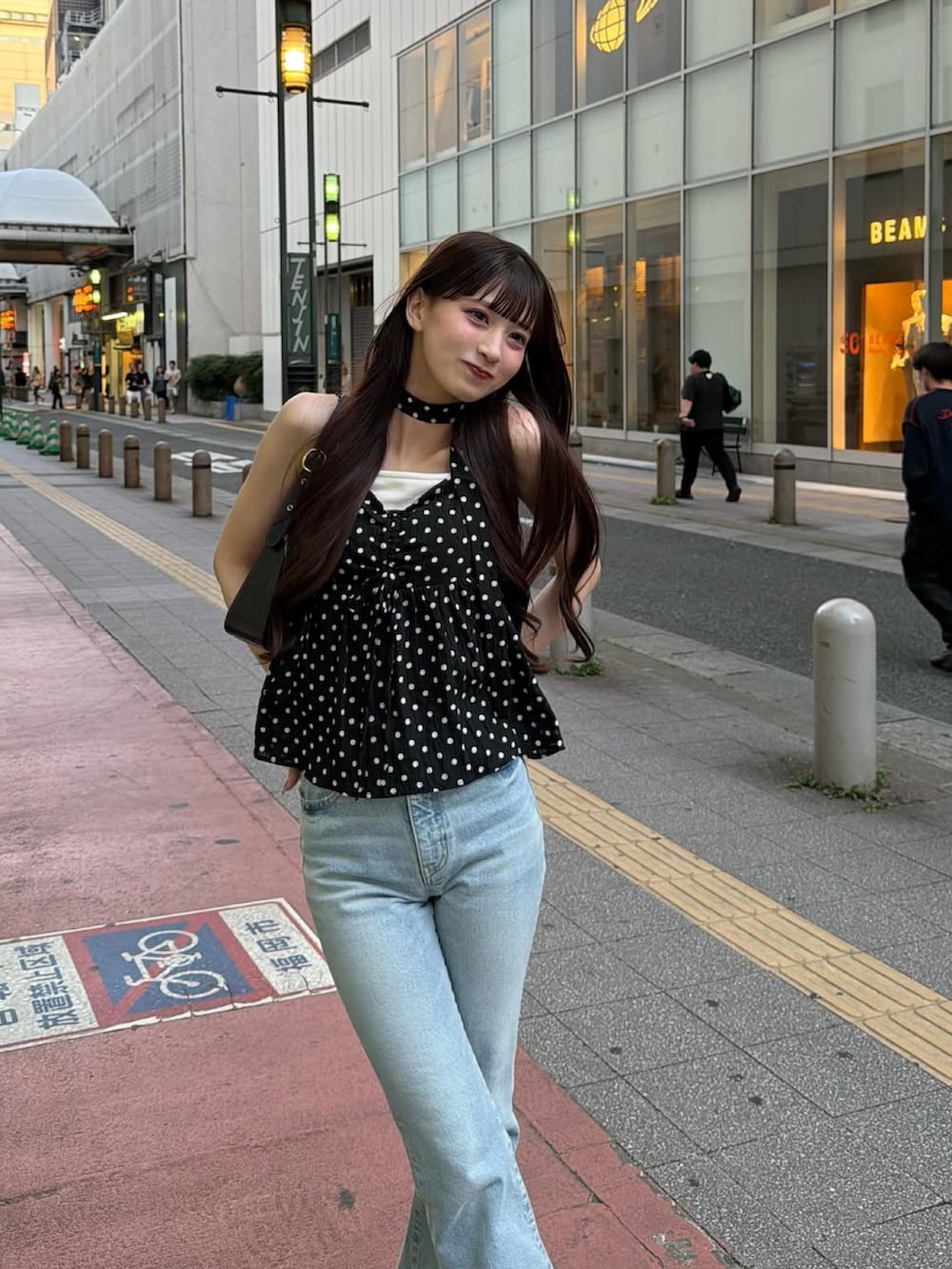 ブラック系のバッグ、ブラック系のトップス、ブルー系のデニムパンツを着用したレディースの夏コーディネートの4枚目の写真