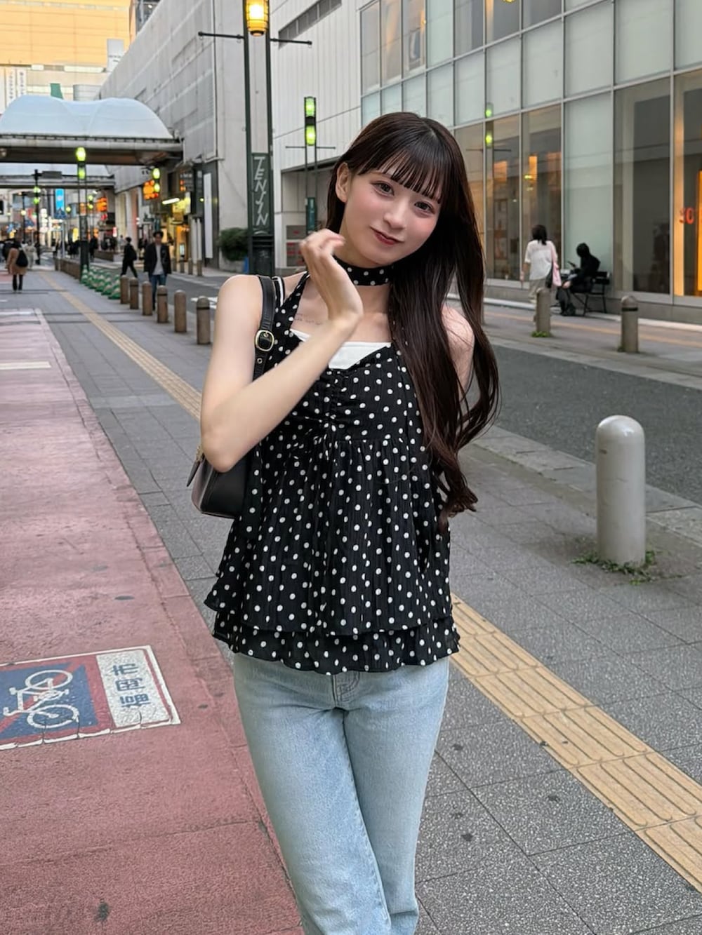 ブラック系のバッグ、ブラック系のトップス、ブルー系のデニムパンツを着用したレディースの夏コーディネートの3枚目の写真