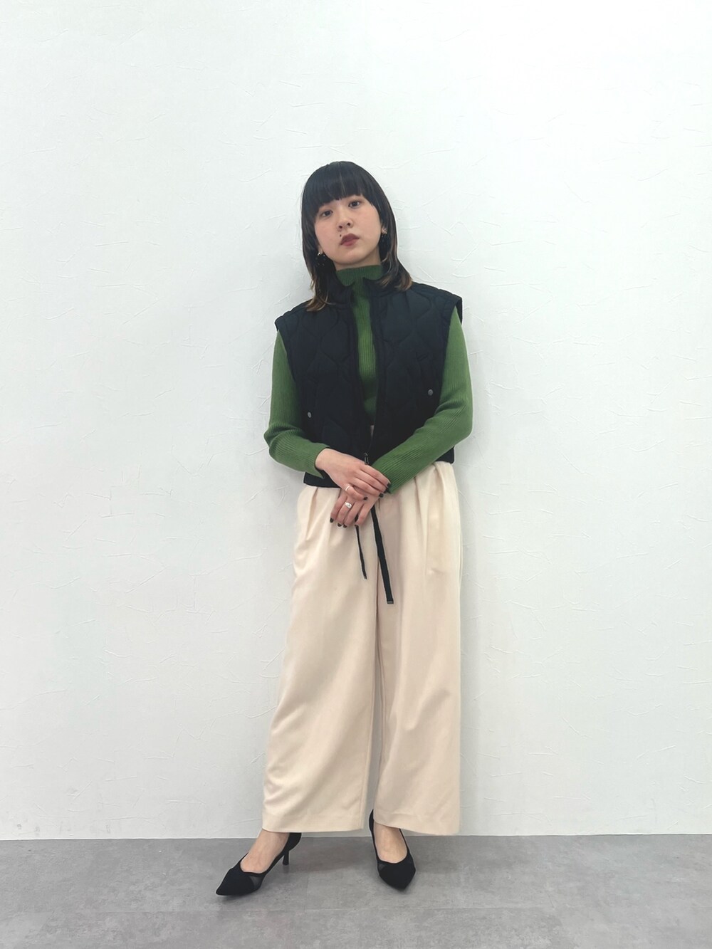 ブラック系のジャケット/アウター、ホワイト系のパンツ、グリーン系のニット/セーターを着用したレディースの冬コーディネートの2枚目の写真