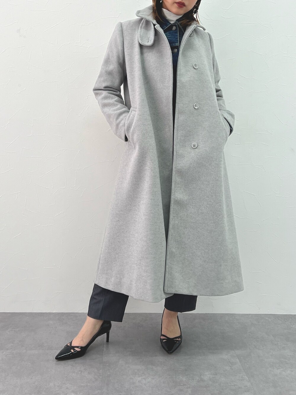 ブルー系のデニムジャケット、グレー系のステンカラーコート、グレー系のパンツを着用したレディースの冬コーディネートの3枚目の写真