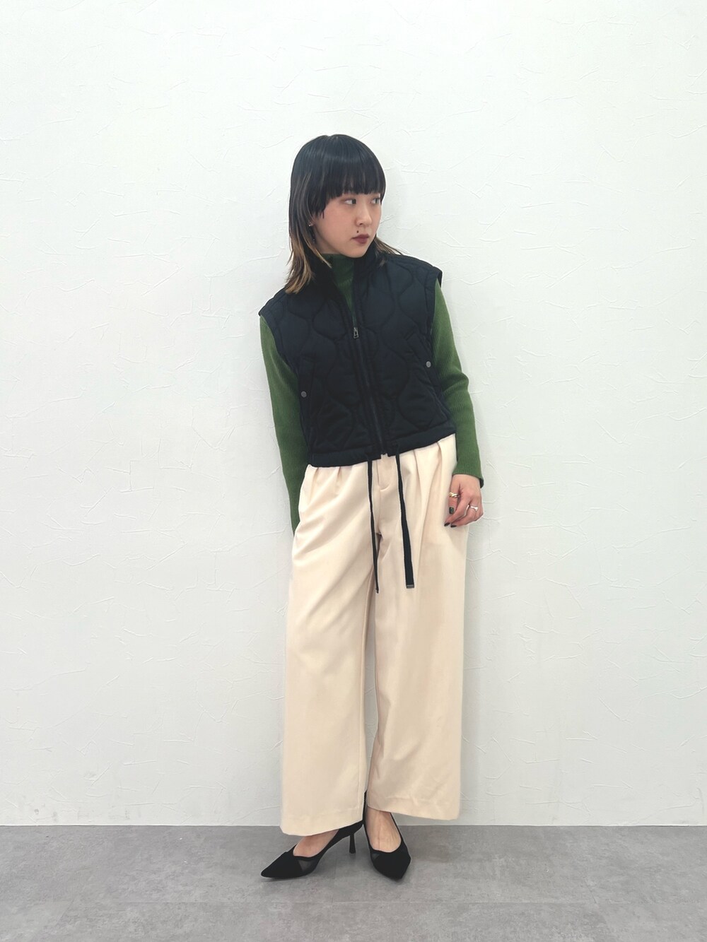 ブラック系のジャケット/アウター、ホワイト系のパンツ、グリーン系のニット/セーターを着用したレディースの冬コーディネートの3枚目の写真