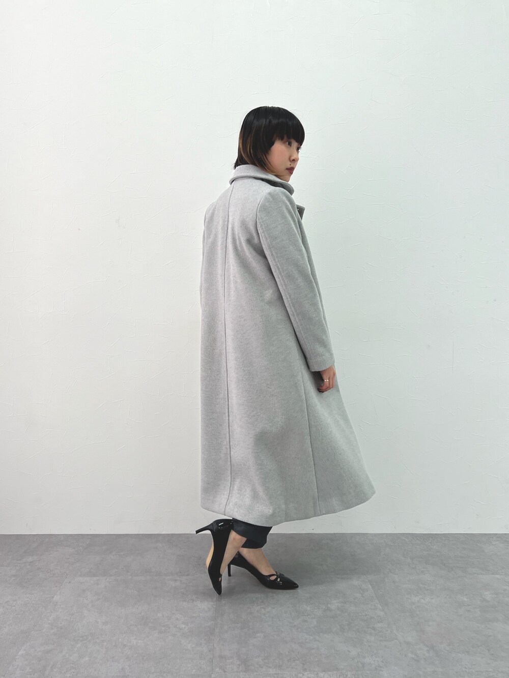 ブルー系のデニムジャケット、グレー系のステンカラーコート、グレー系のパンツを着用したレディースの冬コーディネートの2枚目の写真