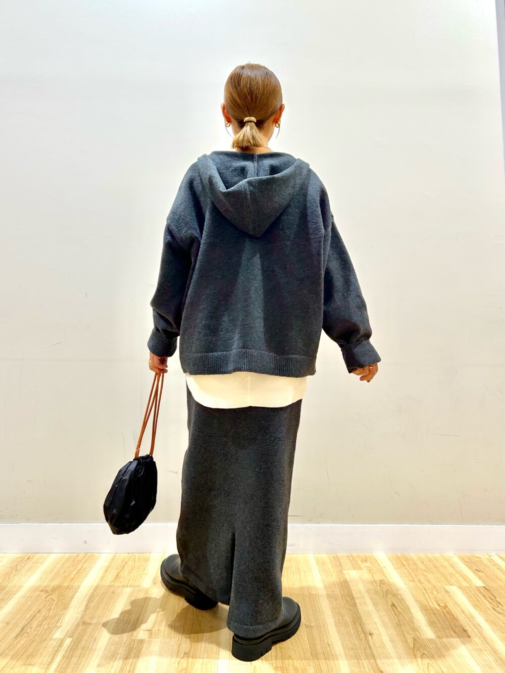 グレー系のニット/セーター、ホワイト系のTシャツ/カットソー、グレー系のスカートを着用したレディースの秋コーディネートの3枚目の写真