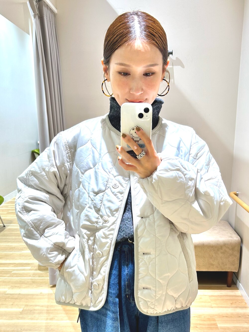 ホワイト系のダウンジャケット/コート、グレー系のニット/セーター、ブルー系のデニムパンツを着用したレディースの冬コーディネートの9枚目の写真