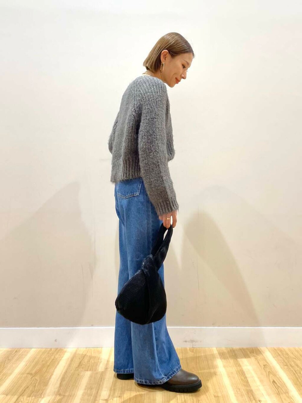 ブラウン系のブーツ、ブルー系のデニムパンツ、ブラック系のハンドバッグを着用したレディースの秋コーディネートの7枚目の写真