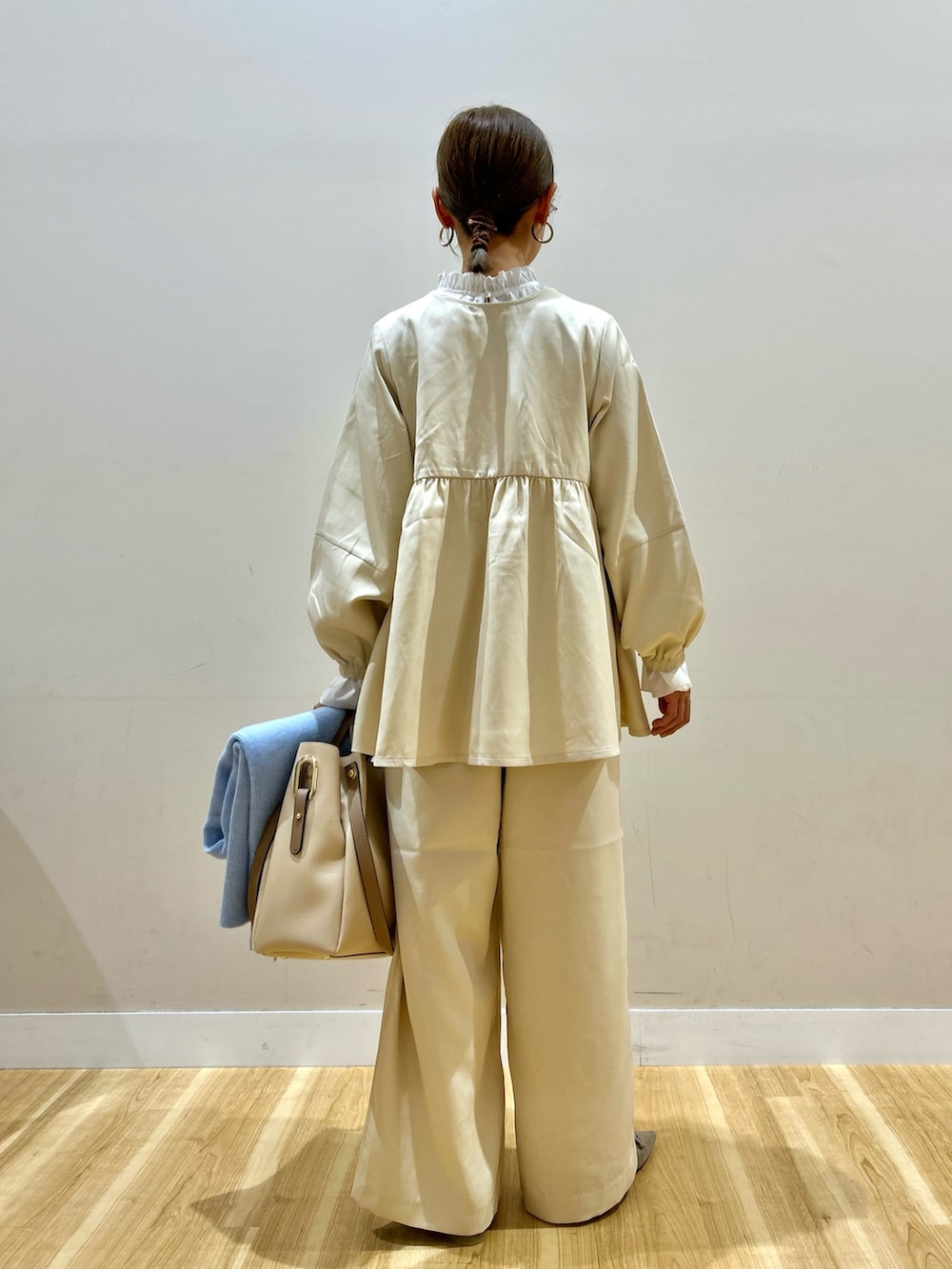 ベージュ系のセットアップ、ホワイト系のトートバッグを着用したレディースの秋コーディネートの3枚目の写真
