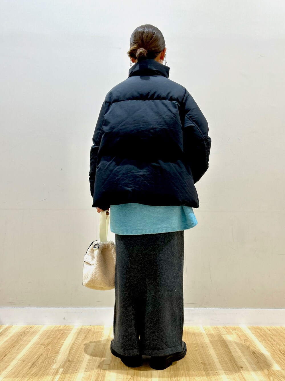 ブラック系のダウンジャケット/コート、ブルー系のニット/セーター、グレー系のスカートを着用したレディースの冬コーディネートの5枚目の写真