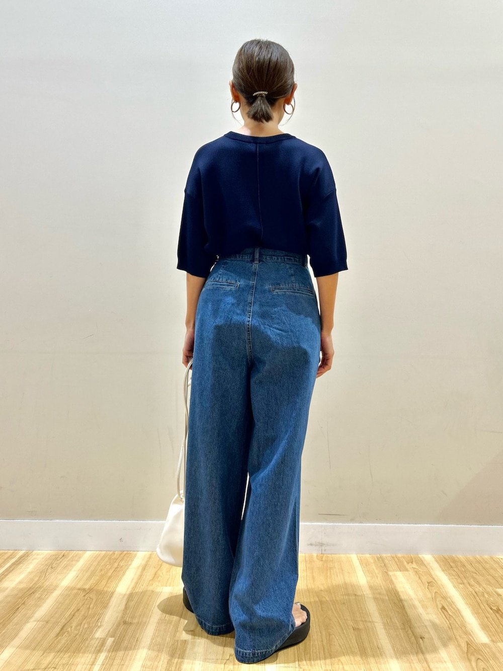 ブルー系のニット/セーター、ブルー系のデニムパンツ、ホワイト系のショルダーバッグを着用したレディースの夏コーディネートの4枚目の写真