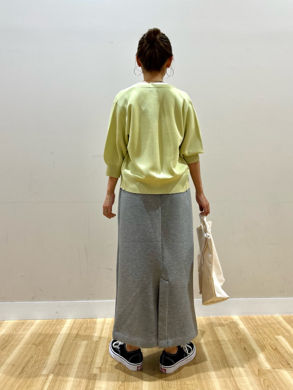 イエロー系のカーディガン/ボレロ、ホワイト系のTシャツ/カットソー、グレー系のスカートを着用したレディースの春コーディネートの3枚目の写真